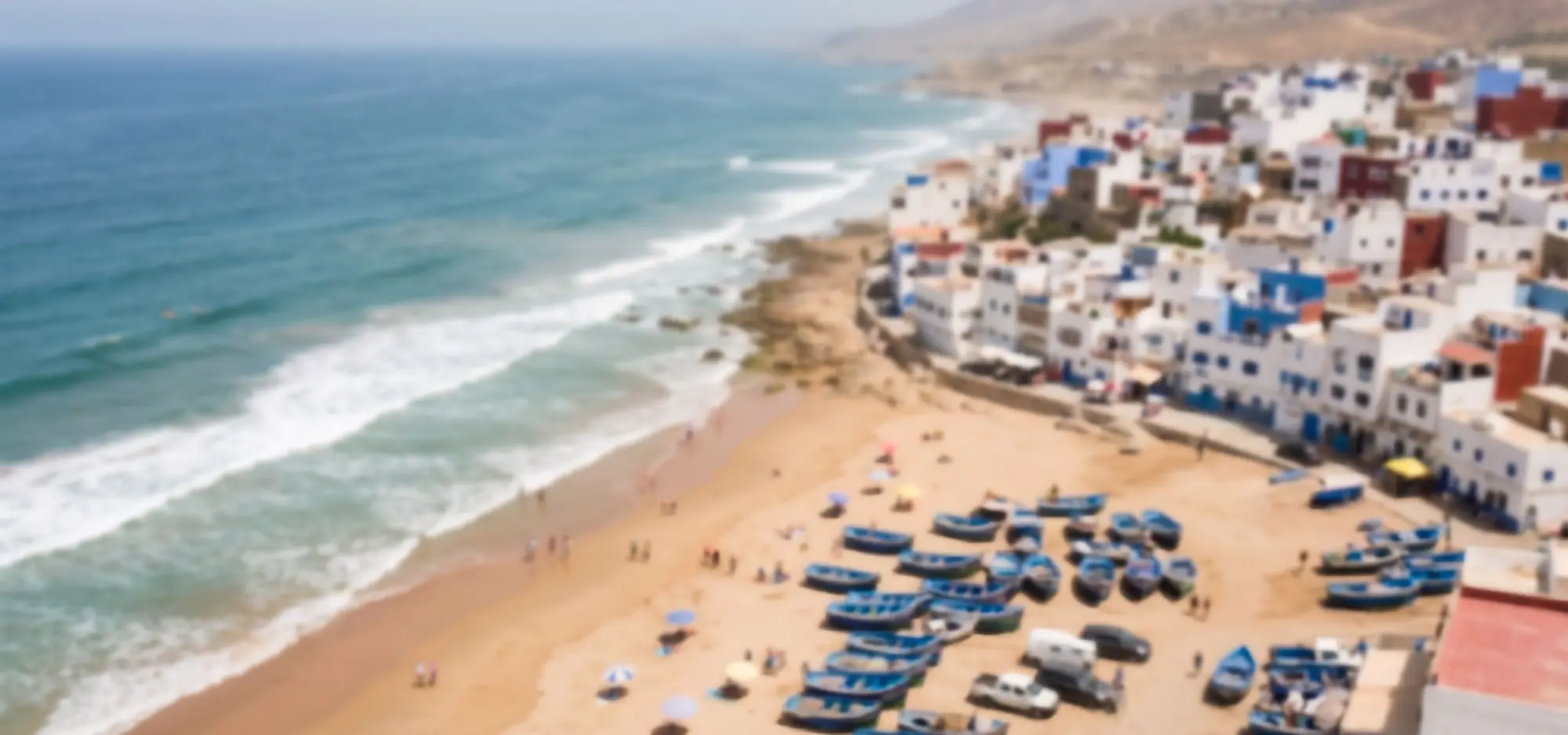Aerial view of Taghazout: white and blue houses above a beach lined with fishing boats