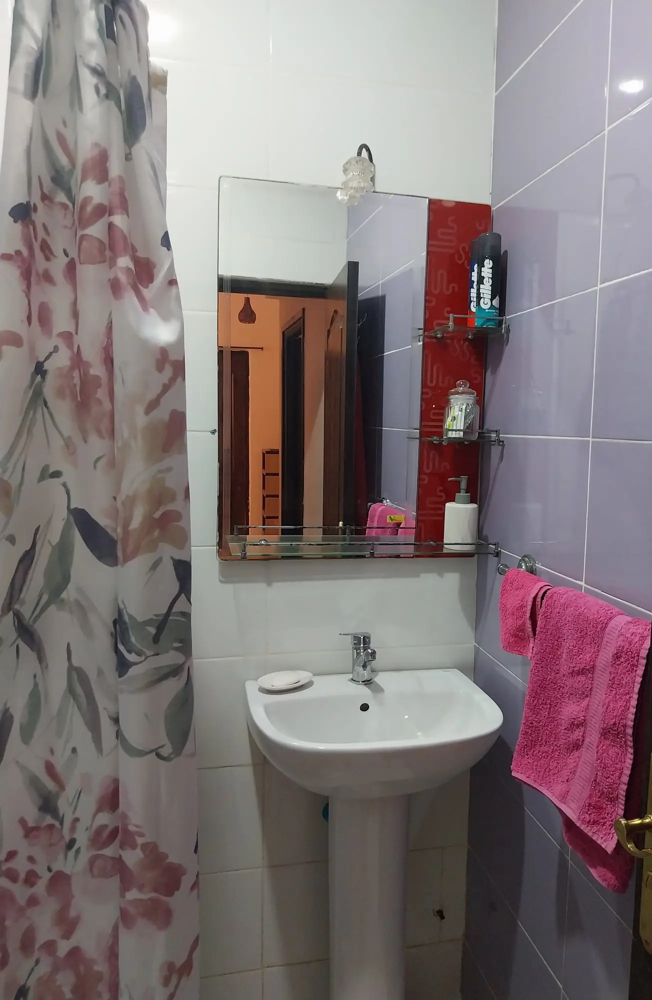 Bathroom washbasin and mirror against lilac tiles