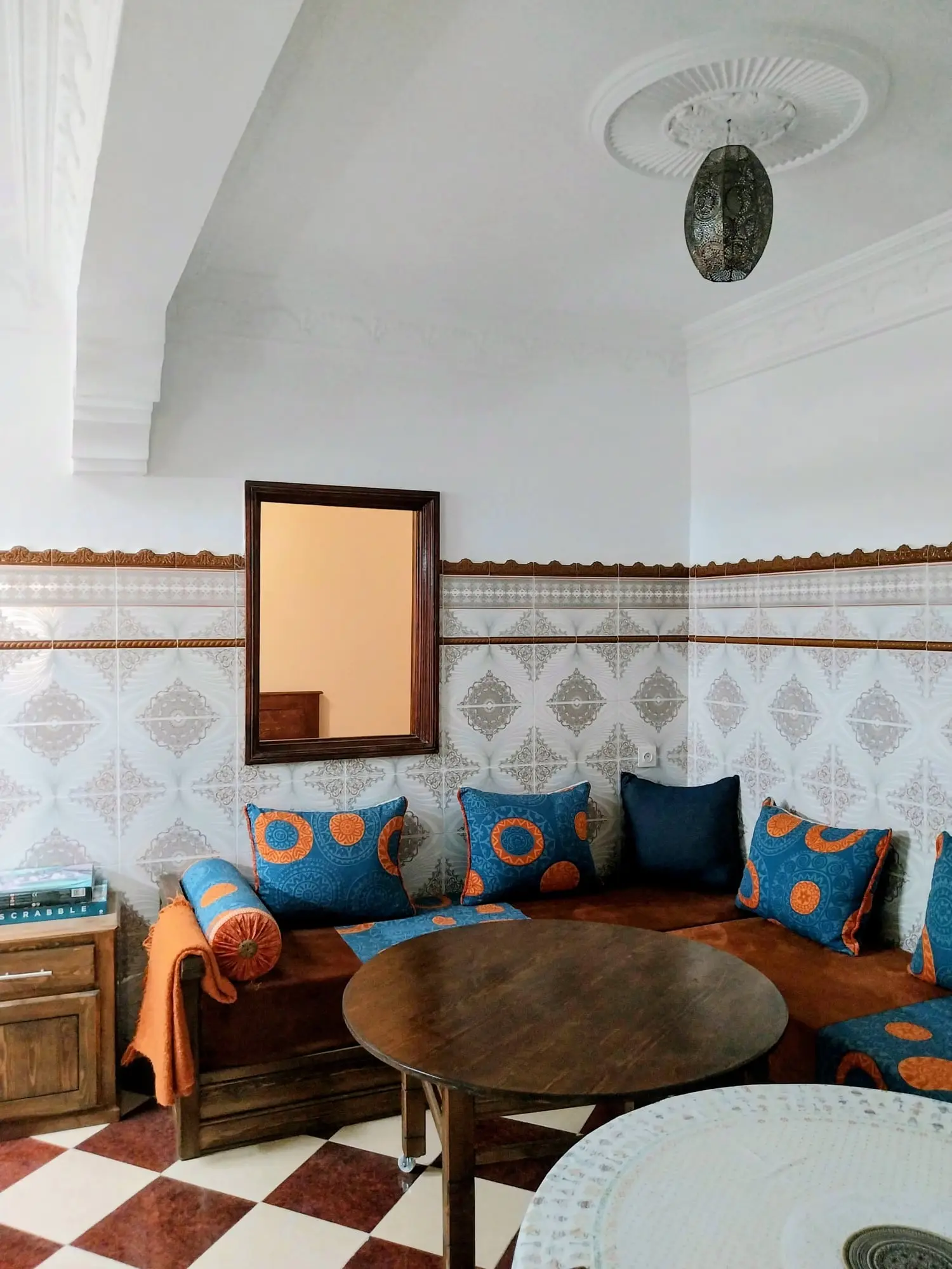 Salon with blue-cushioned banquettes, patterned wall tiles and a checkerboard floor