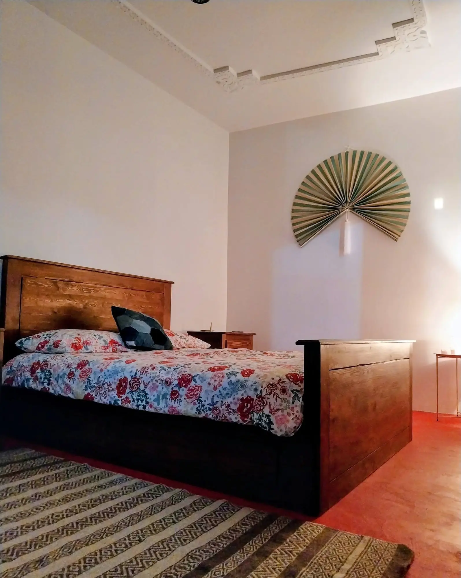 Bedroom with a wooden double bed and a striped rug