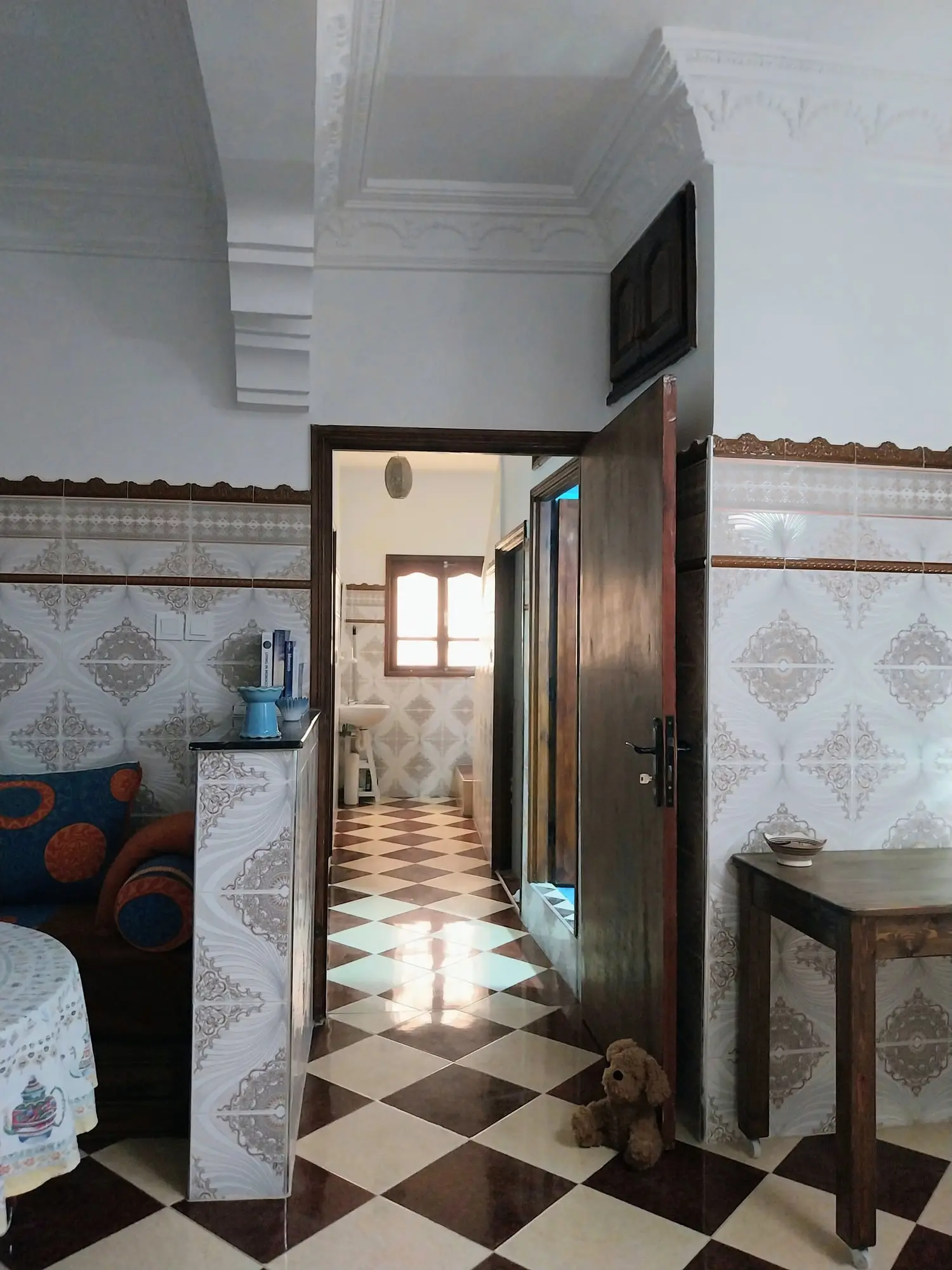 Hallway with a checkerboard floor through an open wooden door
