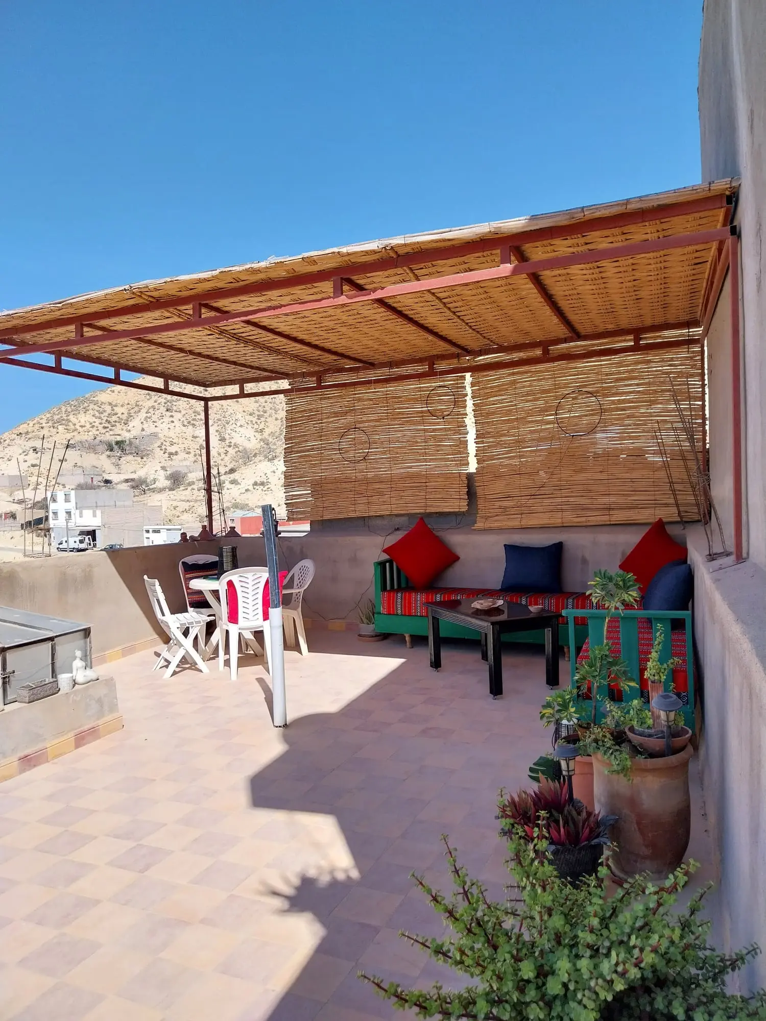 Roof terrace with a reed-shaded seating area and a table and chairs