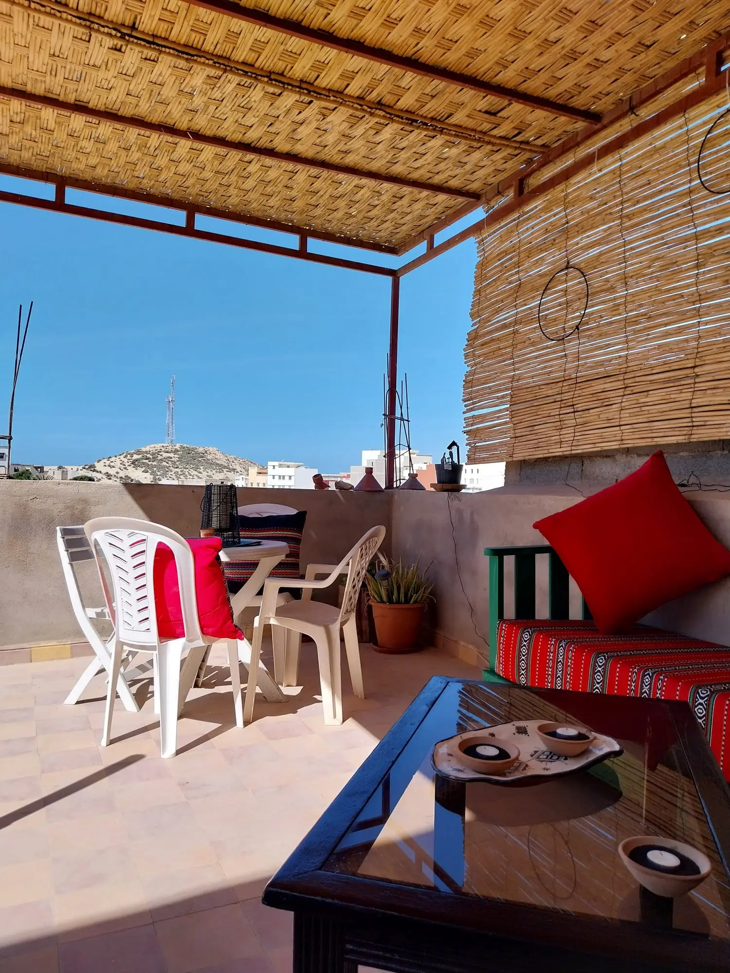 Shaded roof terrace with cushions and a low table, with the sea on the horizon