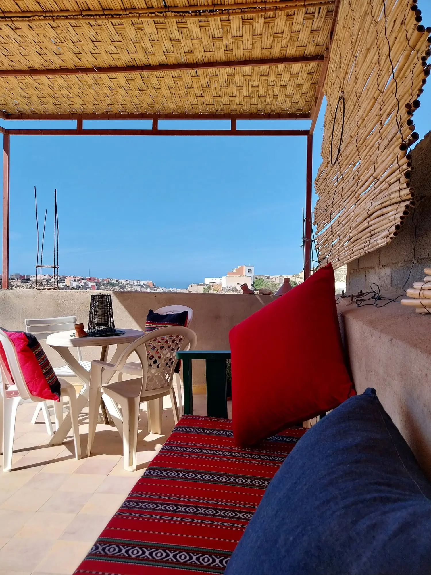 Terrace seating with red and blue cushions under the reed shade