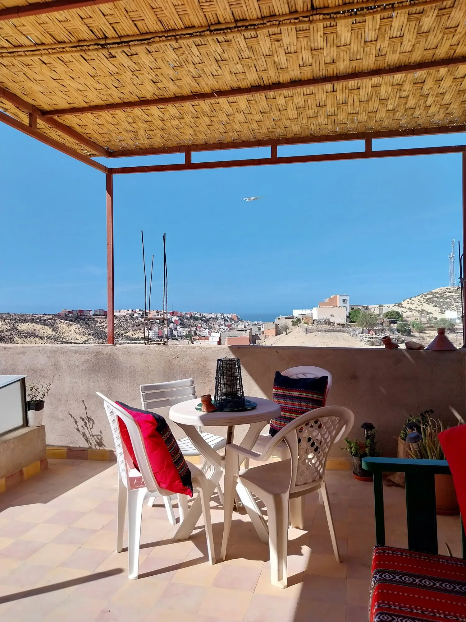 Terrace table and chairs under the shade, looking out to sea